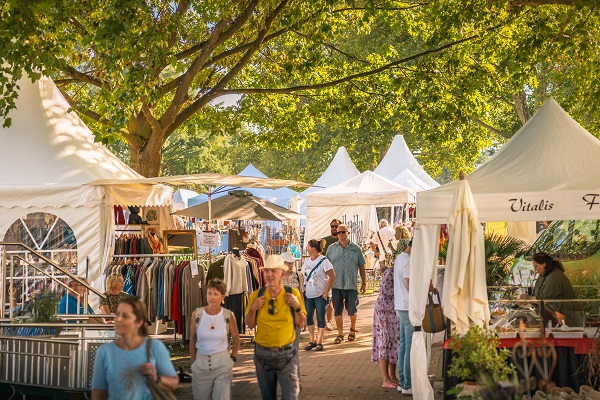 Besucher einer Outdoor-Messe zwischen weißen Zelten mit Austellern