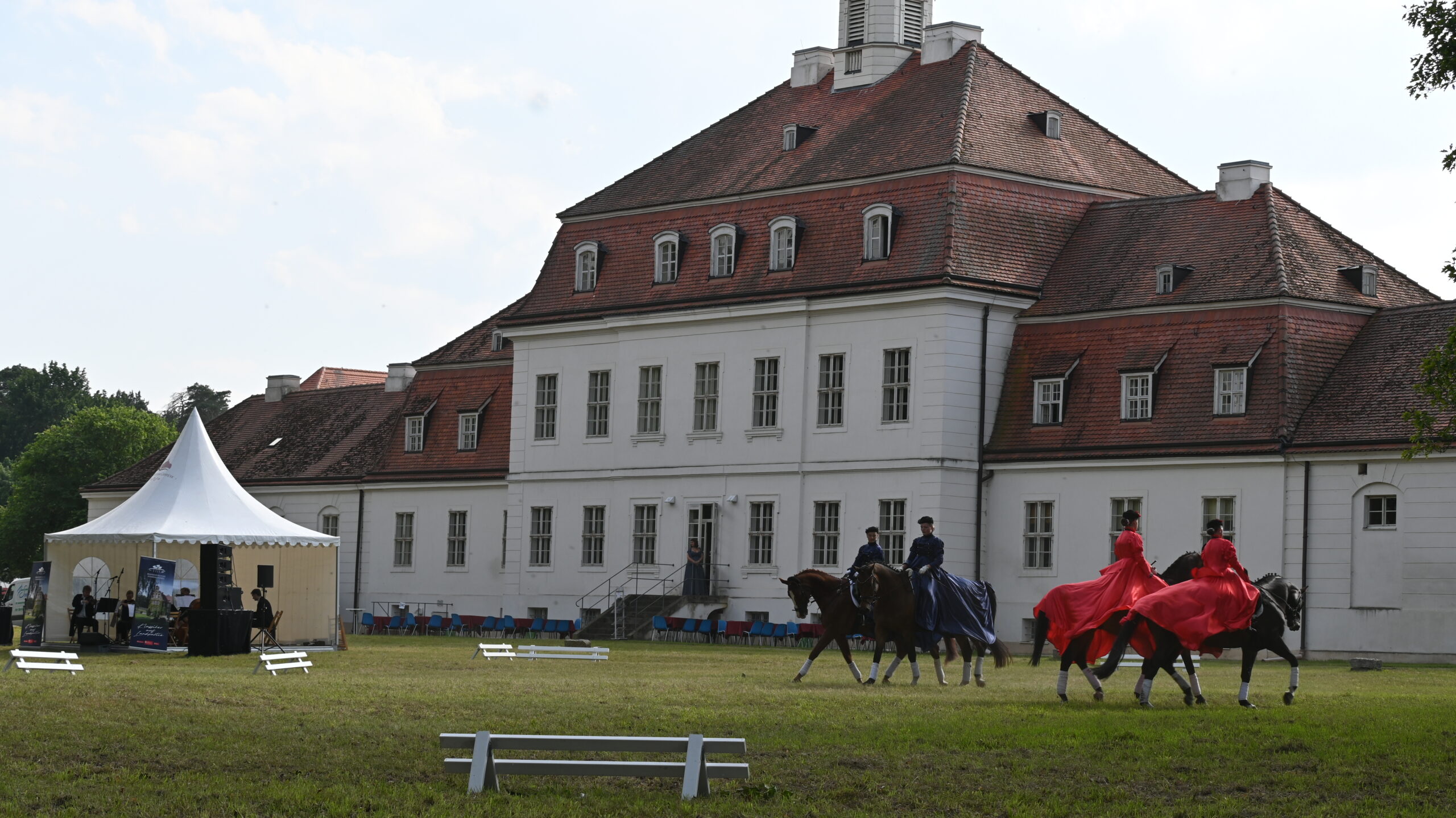 historisches Gebäude davor Reiter mit Kostümen und ein kleines Orchester